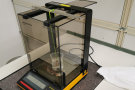 Messgerät mit durchsichtigem Plastebecher steht auf einem Labortisch.
