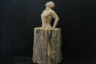 Mann steckt bis zu den Lenden in einem Holzstamm fest und versucht sich mit seinen Armen heraus zu stemmen - Skulptur