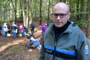 Ein Mann mit Brille und in Uniform der Forstverwaltung steht vor einer Gruppe Kinder und lächelt in die Kamera