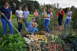 Studierende im Garten mit geerntetem Gemüse