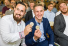 Zwei junge Männer aus dem Publikum halten ihre Medaillen in die Kamera