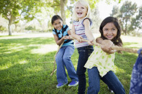 Drei kleine Mädchen im Garten beim Seilziehen. Foto: © Corbis