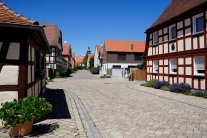 Gepflasterte Dorfgasse von  Fachwerkhäusern umgeben