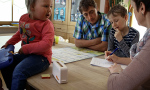 Familie am Küchentisch mit einer Hauswirtschafterin