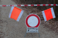 Waldweg versperrt mit einem Absperrband, einem Sperrschild und zwei Fahnen