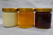 Drei nebeneinander stehende Honiggläser mit verschiedenen (auch farbigen) Sorten.