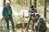 Drei Personen mit Fluchtstab und Meterstab im Wald