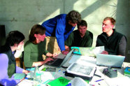 Gruppe Personen an einem Tisch mit Laptop und Unterlagen