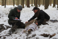 Zwei Personen versehen ein Stück Rotwild in einem Winterwald mit einem Sender.