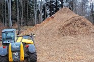 Bagger neben einem Berg Hackschnitzel