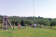 Neben einem Hochsitz sind in einer Reihe verschiedene Geräte angeordnet unter anderem zwei Solar Panels und eine große Antenne. 