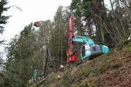 Yarder im Wald am Hang seilt Vollbäume nach oben.