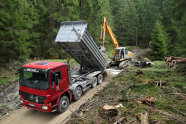 Aufbringen von Tragschichtmaterial mittels LKW und Bagger bei einem Wegeneubau (© Klaus Lamatsch, AELF KF)