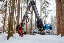 Forstmaschine mit Kran in verschneiten Winterwald