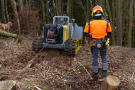 Gelb-graue Rückeraupe mit Bediener beim Vorrücken von Holz.