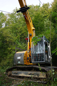 Gelber Bagger mit Seilwinde rückt Holz im Wald.