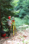 Mann steht mit Messgerät auf Stativ im Wald.