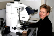 Frau sitzt vor einem Mikroskop