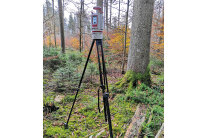Messgerät auf einem Stativ steht im Wald auf Moos bewachsenem Boden.