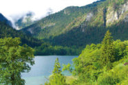 Blick in Landschaft mit Wald, See und Bergen.