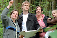 Försterin berät eine junge Familie in ihrem Wald.