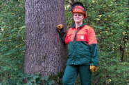 Frau in persönlicher Schutzausrüstung an einen Baum gelehnt