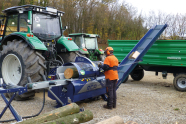 Mann mit Traktor und kombiniertem Säge-Schneidspalter, mit dessen Hilfe Brennholz produziert wird.