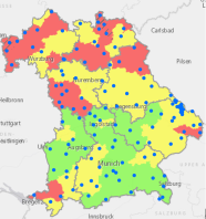 Bayernkarte mit verschiedenen Farben zur Gefährdungseinschätzung. Grün steht für keine Gefahr, gelb für eine Warnstufe ujd rot für Gefahr. Die blauen Punkte sind die Standorte der Kontrollfallen in Bayern.