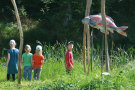 Skulptur eines Koi inmitten von Reis mit Kindern daneben stehend