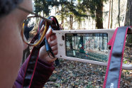 Eine junge Frau blickt auf ein Smartphone, das mit Hilfe der Kamera die realität auf ads Display schickt