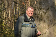 Ein Mann in Uniform der Forstverwaltung steht an einem Baum