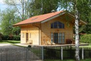 Ein Holzhaus im Bauhaus-Stil umgeben von Hecken, Rasen und Bäumen