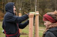 Studierende binden einen Baum mit Stricken an einer Halterung fest.