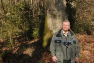 Ein Mann in Uniform der Forstverwaltung steht vor einer mächtigen Buche