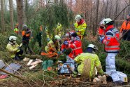 Übungssituation im Forst bei der ein unter dem Baum liegender Patient versorgt wird