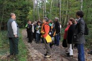 Ein Mann steht mit einer Gruppe Menschen im Wald und gibt einen Vortrag