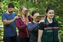 Gruppe beim Laufen durch den Wald mit Spiegel, sodass man das Kronendach anschaut.