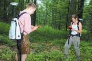 Zwei Personen mit kleinen Geräten im Wald