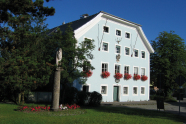 Ein blaues Haus mit Blumenkästen, in denen rote Blumen wachsen inmitten von Grün