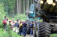 Auf einem Waldweg stehen Kinder und Erwachsenen neben einem Forwarder. 